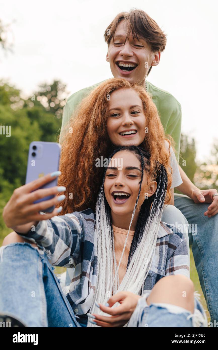 Drei moderne Freunde spielen im Sommerpark in der Social Media App Musik-Aufnahmen-Vlog. Glückliche Kinder können zu Hause spielen und Hobby lernen. Stockfoto