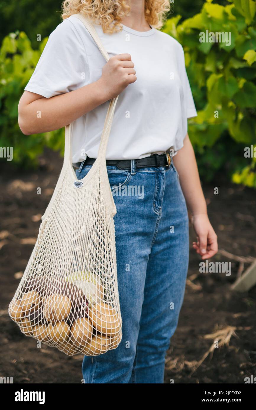 Porträt eines unbekannten Mädchens, das einen Einkaufstasche aus Baumwollstring mit Gemüse hält. Umweltfreundlicher Style. Kein Kunststoff. Modernes, wiederverwendbares Shopping, Zero Waste Konzept. Stockfoto