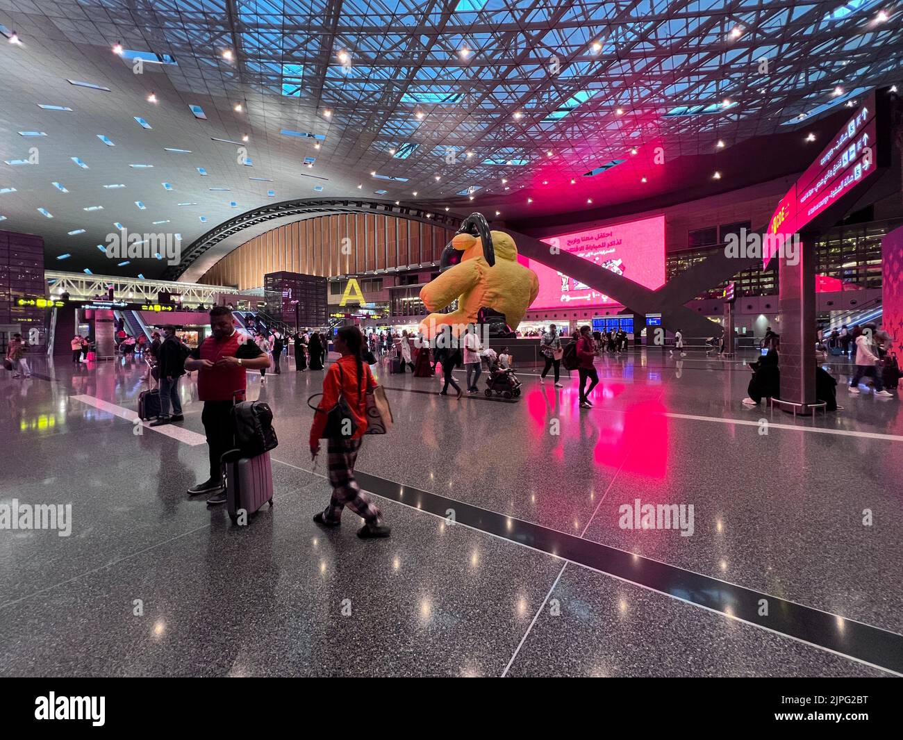 Innenraum des Hamad International Airport Terminal voll von Touristen Passagier, Big Yellow Bear Skulptur, Stockfoto