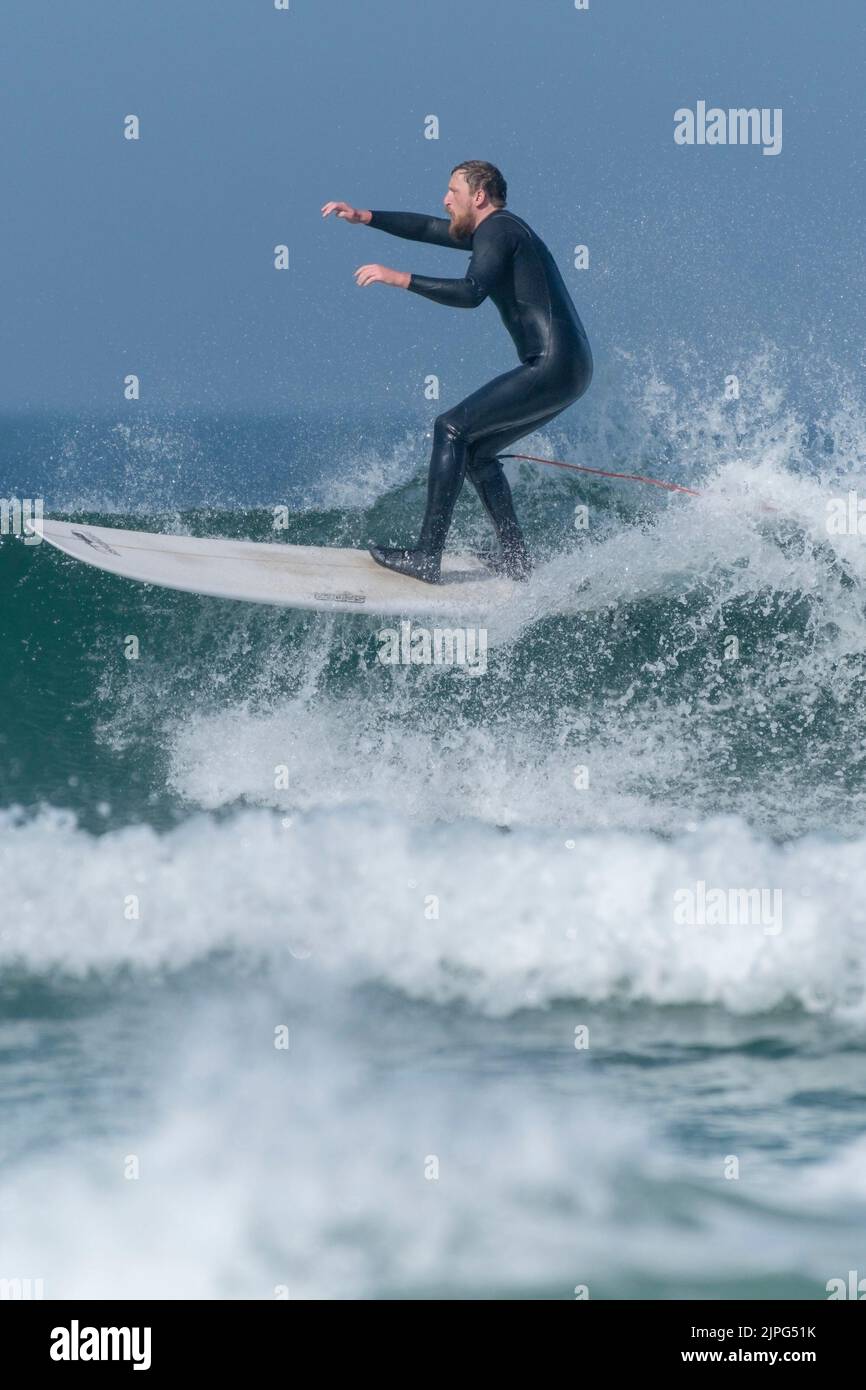 Ein männlicher Surfer, der auf einer Welle bei Fistral in Newquay in Cornwall in Großbritannien reitet. Stockfoto