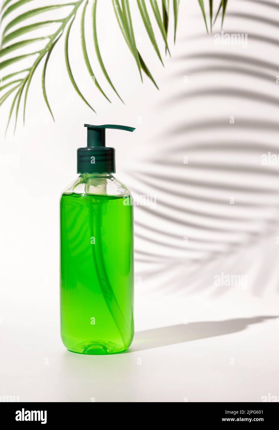 Nachfüllbare Kosmetische Pumpe Spender Flasche mit grüner Flüssigkeit auf weiß gefüllt, Palm Blatt harte Schatten, close up, mockup. Hautpflege Beauty-Produkt, Gesichtsbehandlung Stockfoto