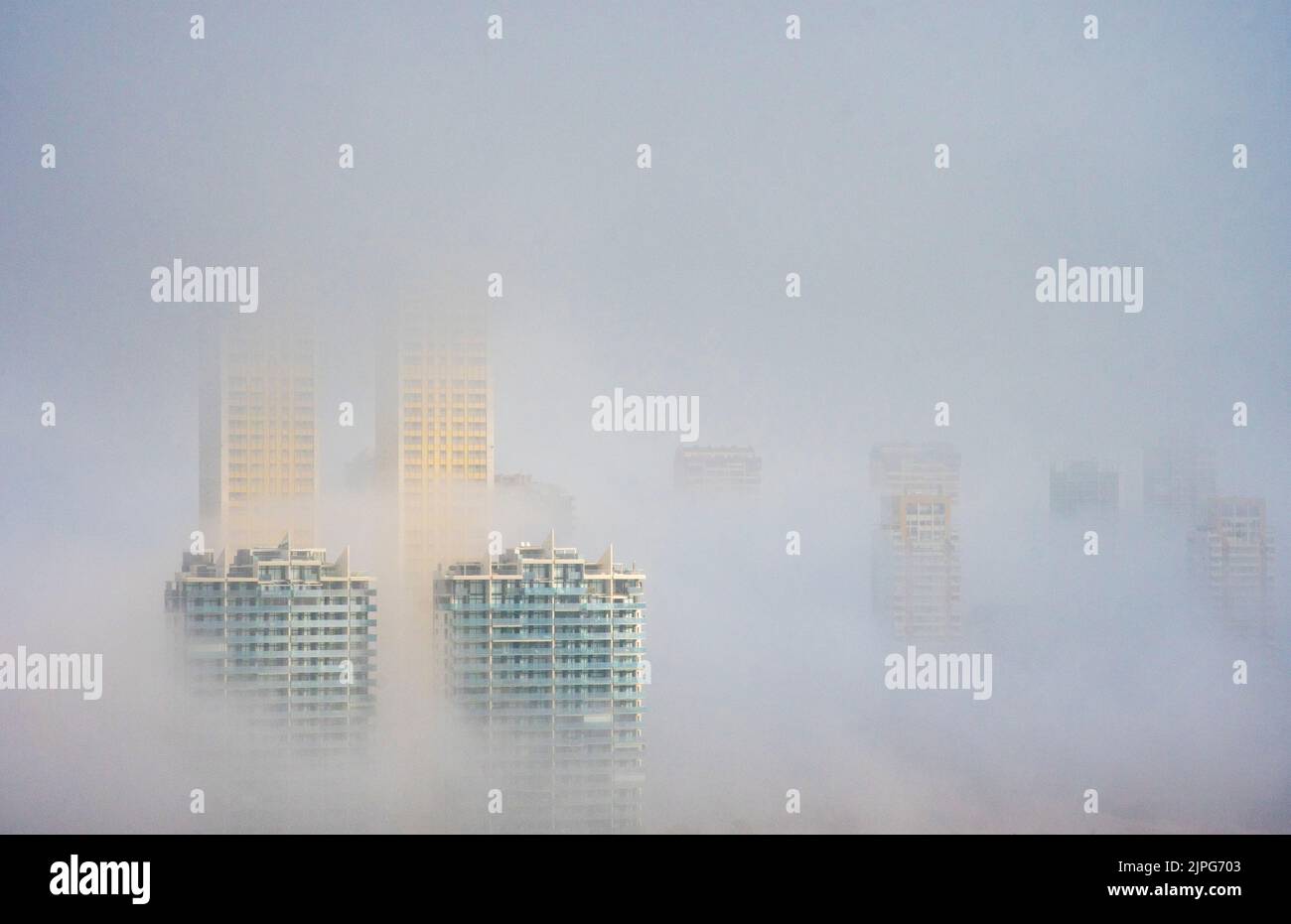 Der Gipfel des Intempo Wolkenkratzers erhebt sich über dem Nebel, umgeben von Hochhäusern in Benidorm, Spanien Stockfoto