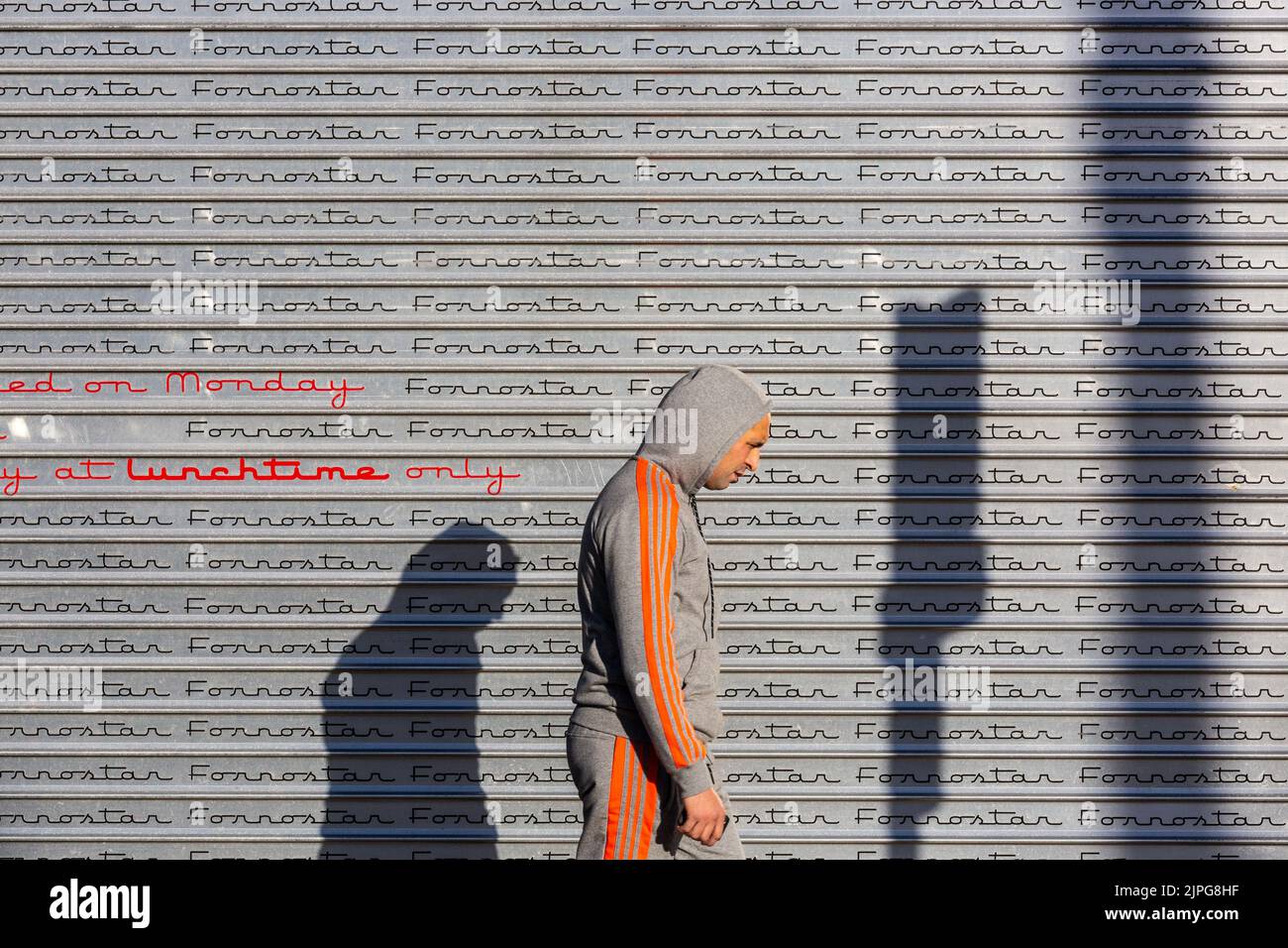 Mann, der an einem grauen Fensterladen vorbeigeht Stockfoto