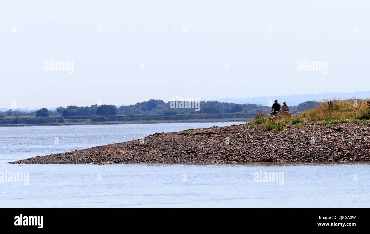 Zwei Wanderer sitzen am steinigen Ausbiss von Barnkirk Point, wo der Fluss Annan in den solway Firth, Schottland, mündet Stockfoto