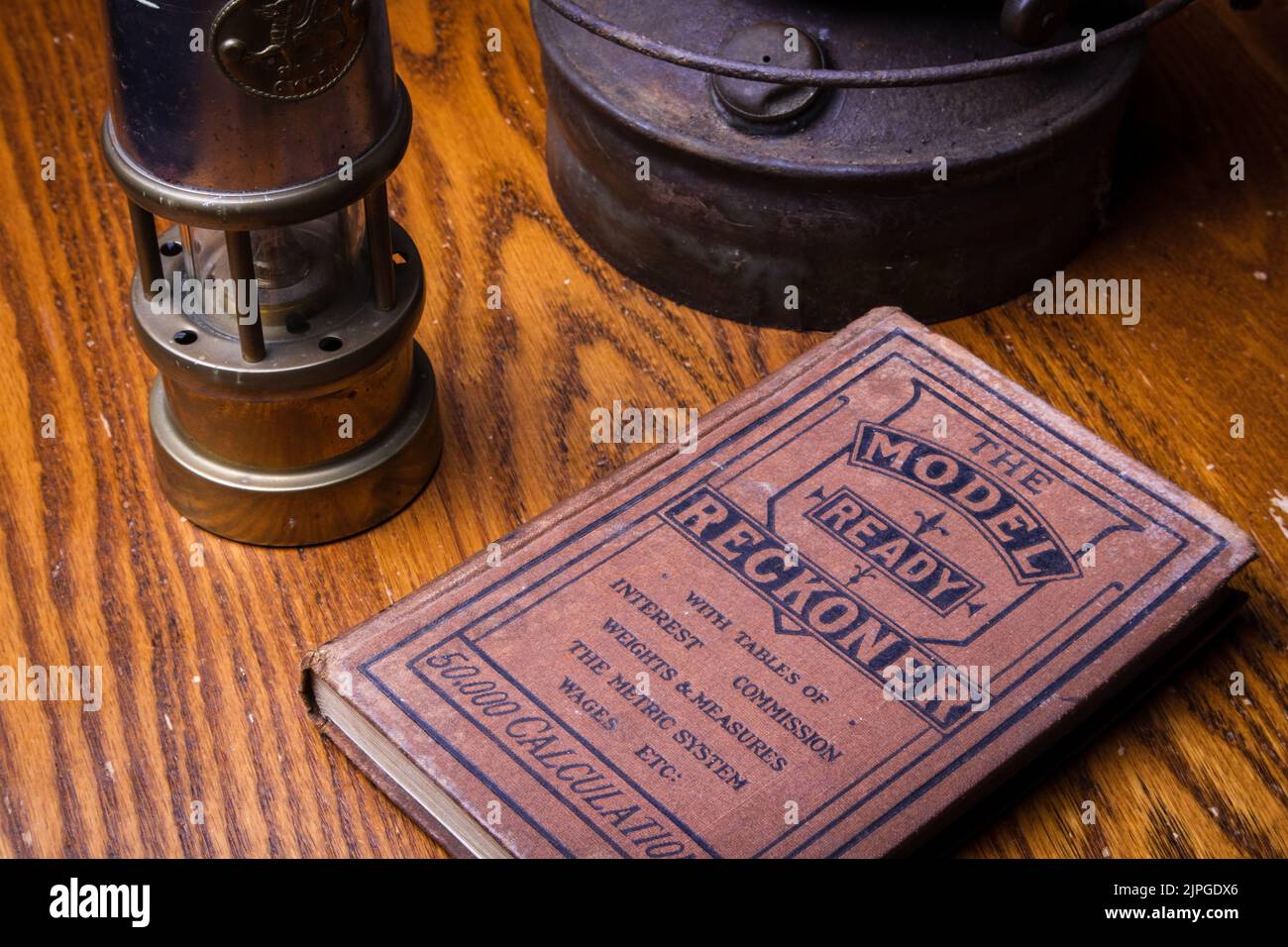 Eine Nahaufnahme von alten Gewichten und Maßbüchern vor einer Ölgaslampe. Stockfoto