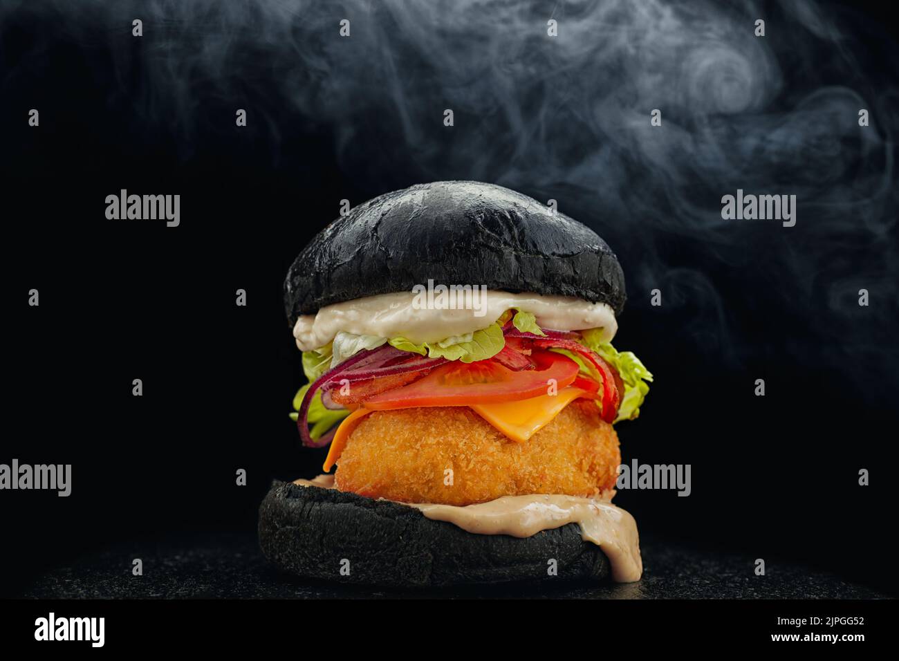Black Burger mit Patty in Paniermehl auf schwarzem Hintergrund und Rauch Stockfoto