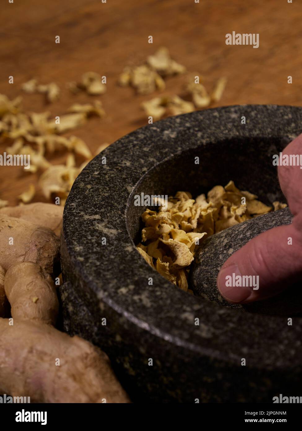 Getrockneter und frischer Ingwer mit einem Mörser und Stößel auf einem Holzschneidebrett Stockfoto