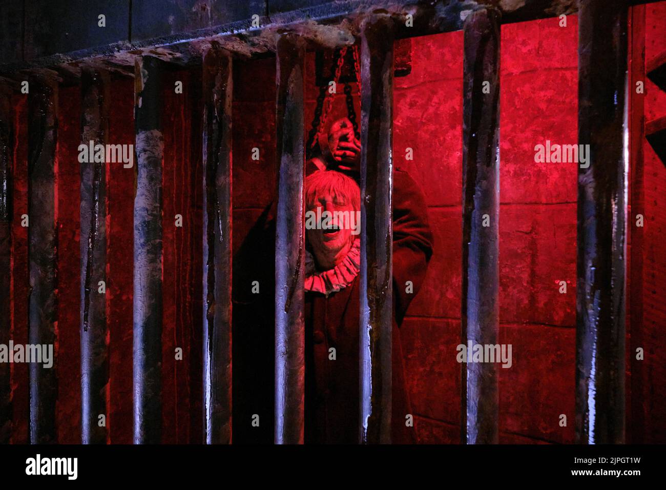Eine Frau, die in einer Gefängniszelle mit buntem Lichteffekt angekettet wurde. Im Clink Prison Museum, Southbank Thames, London, Großbritannien. Stockfoto