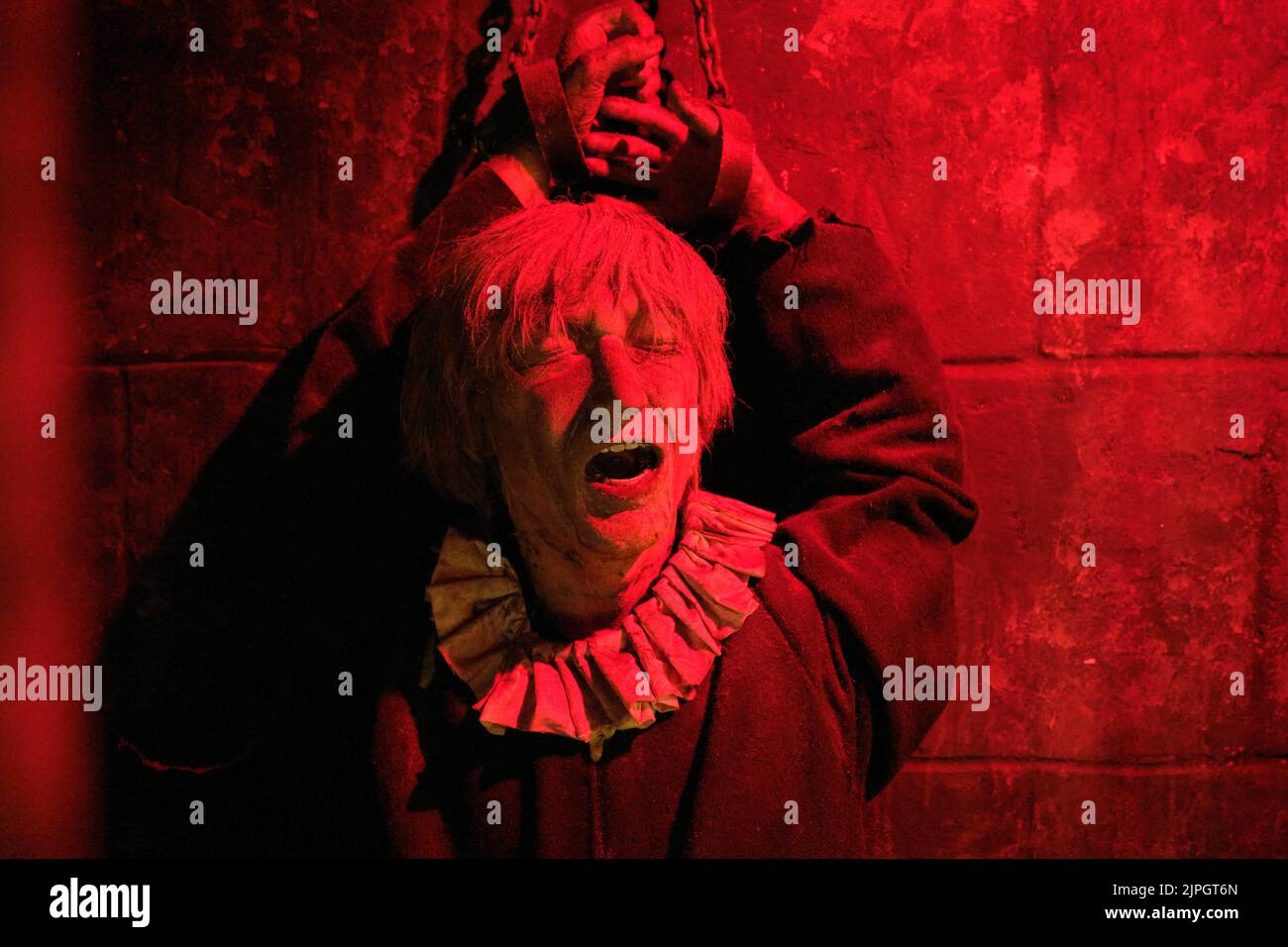 Eine Frau, die in einer Gefängniszelle mit buntem Lichteffekt angekettet wurde. Im Clink Prison Museum, Southbank Thames, London, Großbritannien. Stockfoto