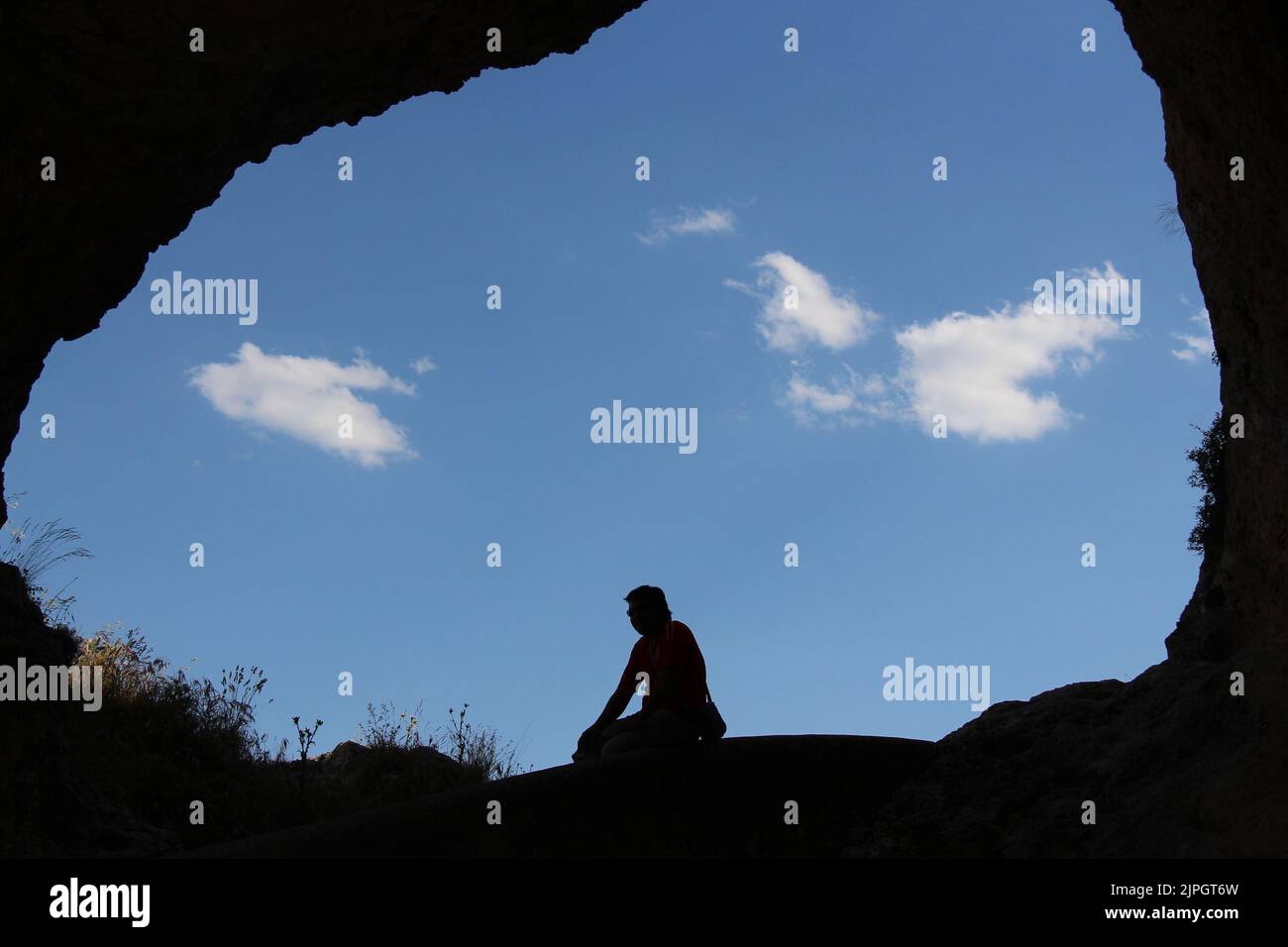 Person, die am Eingang einer Höhle in Guadalajara, Spanien, meditiert Stockfoto