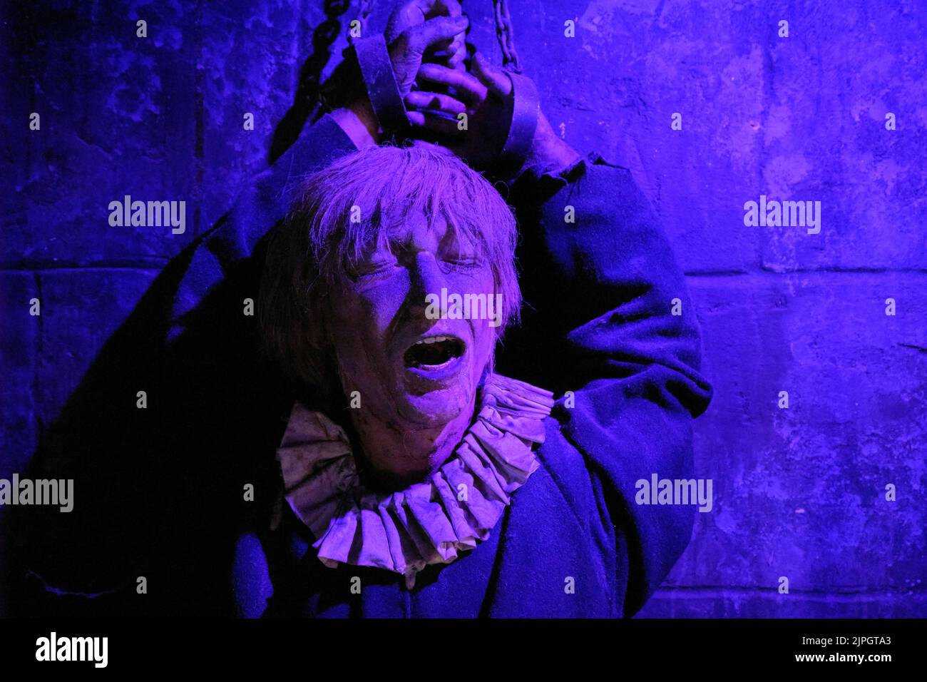 Eine Frau, die in einer Gefängniszelle mit buntem Lichteffekt angekettet wurde. Im Clink Prison Museum, Southbank Thames, London, Großbritannien. Stockfoto