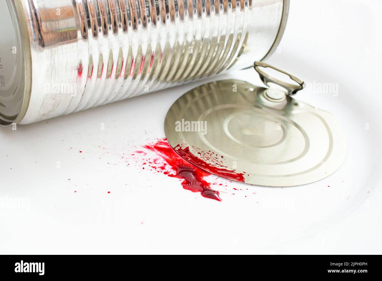 Aluminiumdose mit Blutspritzer auf weißem Hintergrund, Hausverletzungskonzept, Nahaufnahme Stockfoto