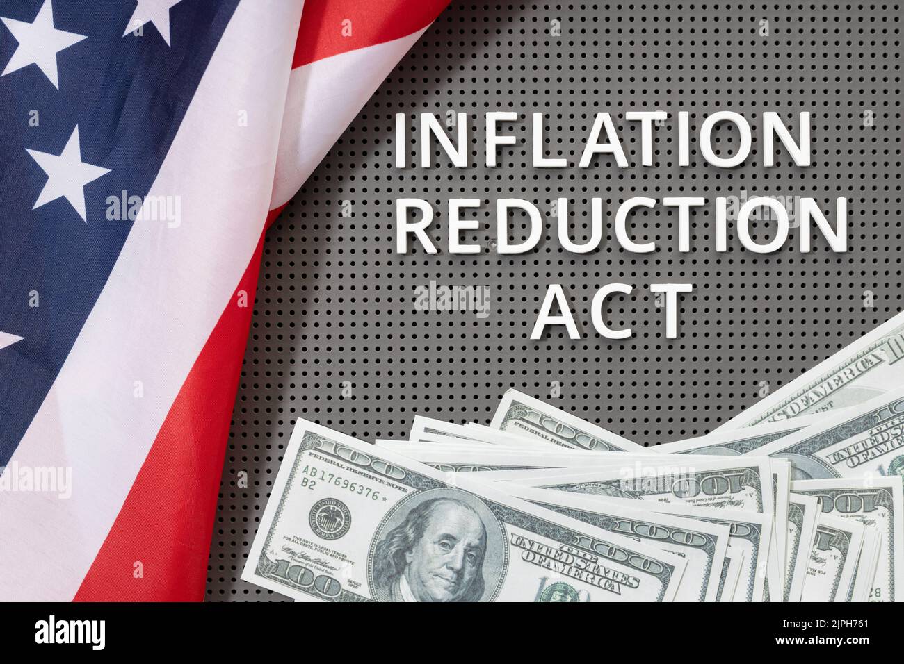 Gesetzeskonzept des Inflationsminderungsgesetzes. Fette Lay von Text, amerikanischer Flagge und Dollar-Banknoten Stockfoto