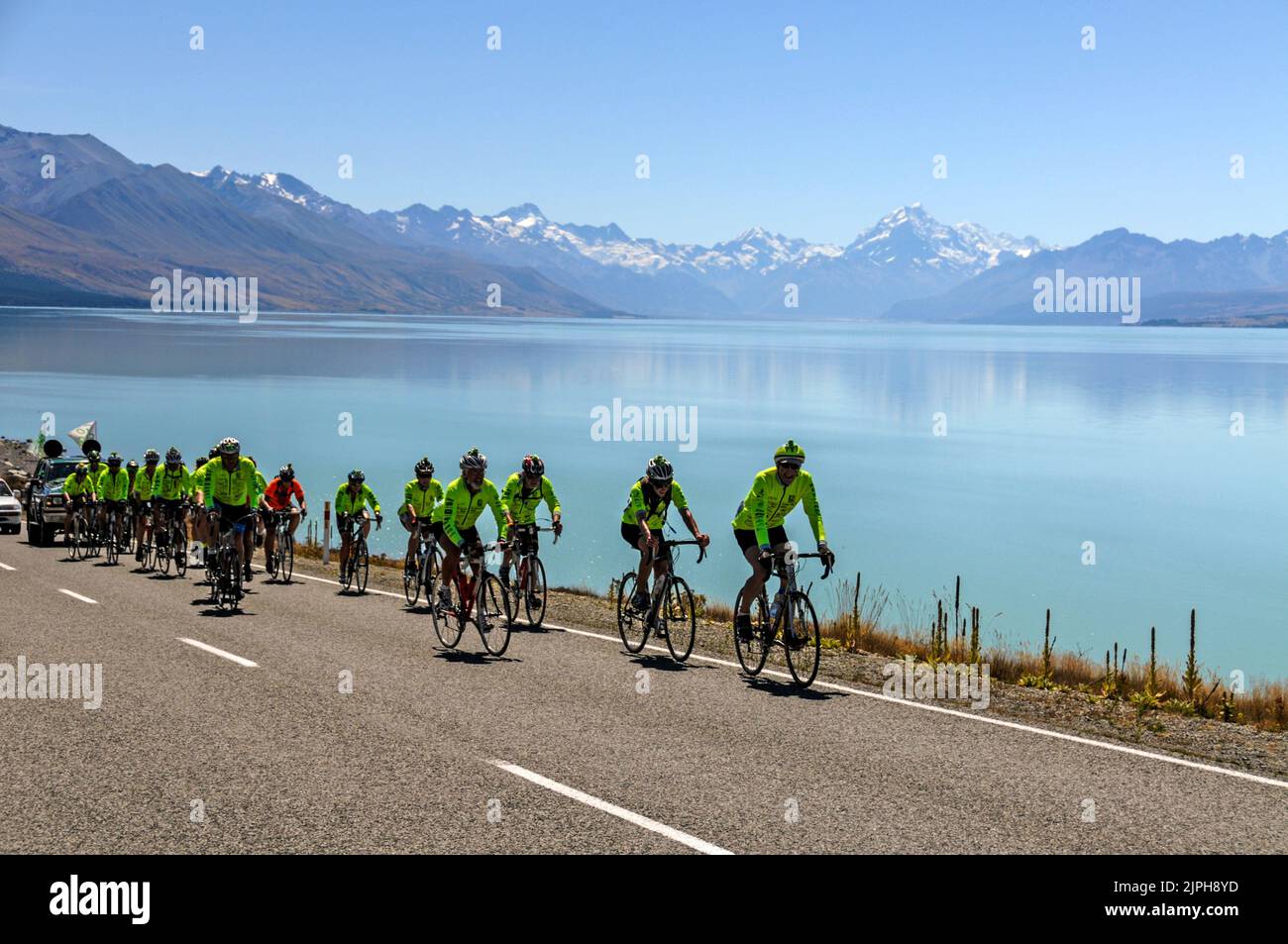 Am Ufer des Lake Tekapo im Mackenzie Country, South Island, in Neuseeland, führt ein Radrennen zur Unterstützung von Wohltätigkeitsorganisationen auf dem State Highway 8 entlang. In der Ferne Stockfoto