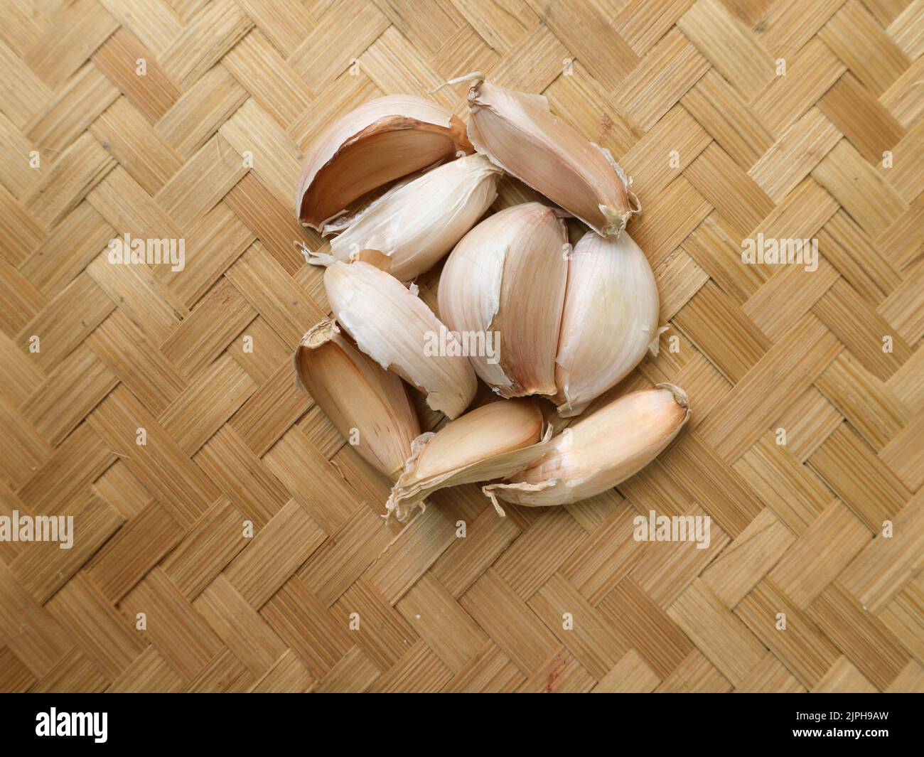 Ungeschälter Knoblauch auf einem gewebten Bambus-Hintergrund Stockfoto