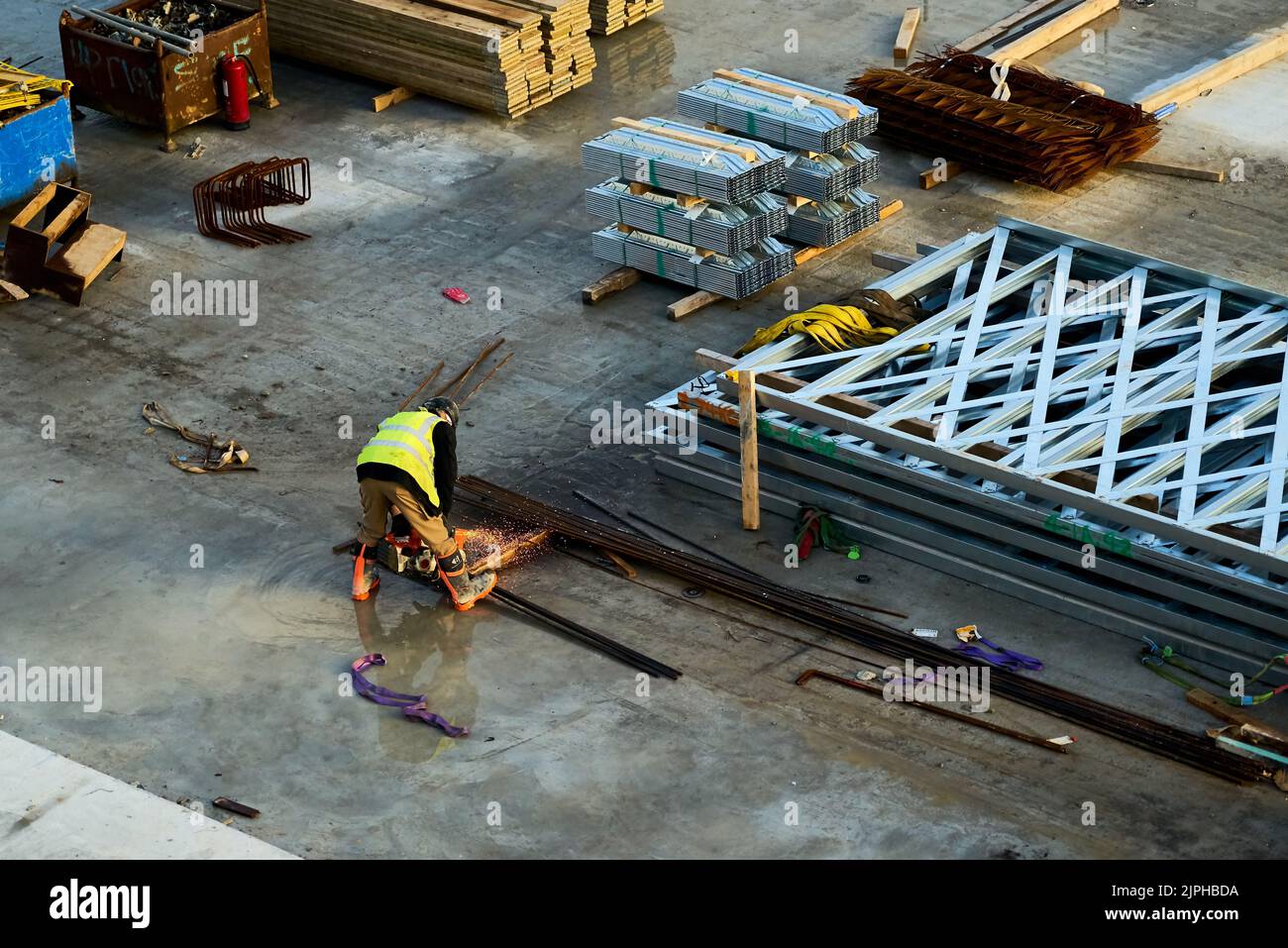 Ein Bauarbeiter verwendet einen Winkelschleifer, um Metall im Baubereich zu schneiden Stockfoto