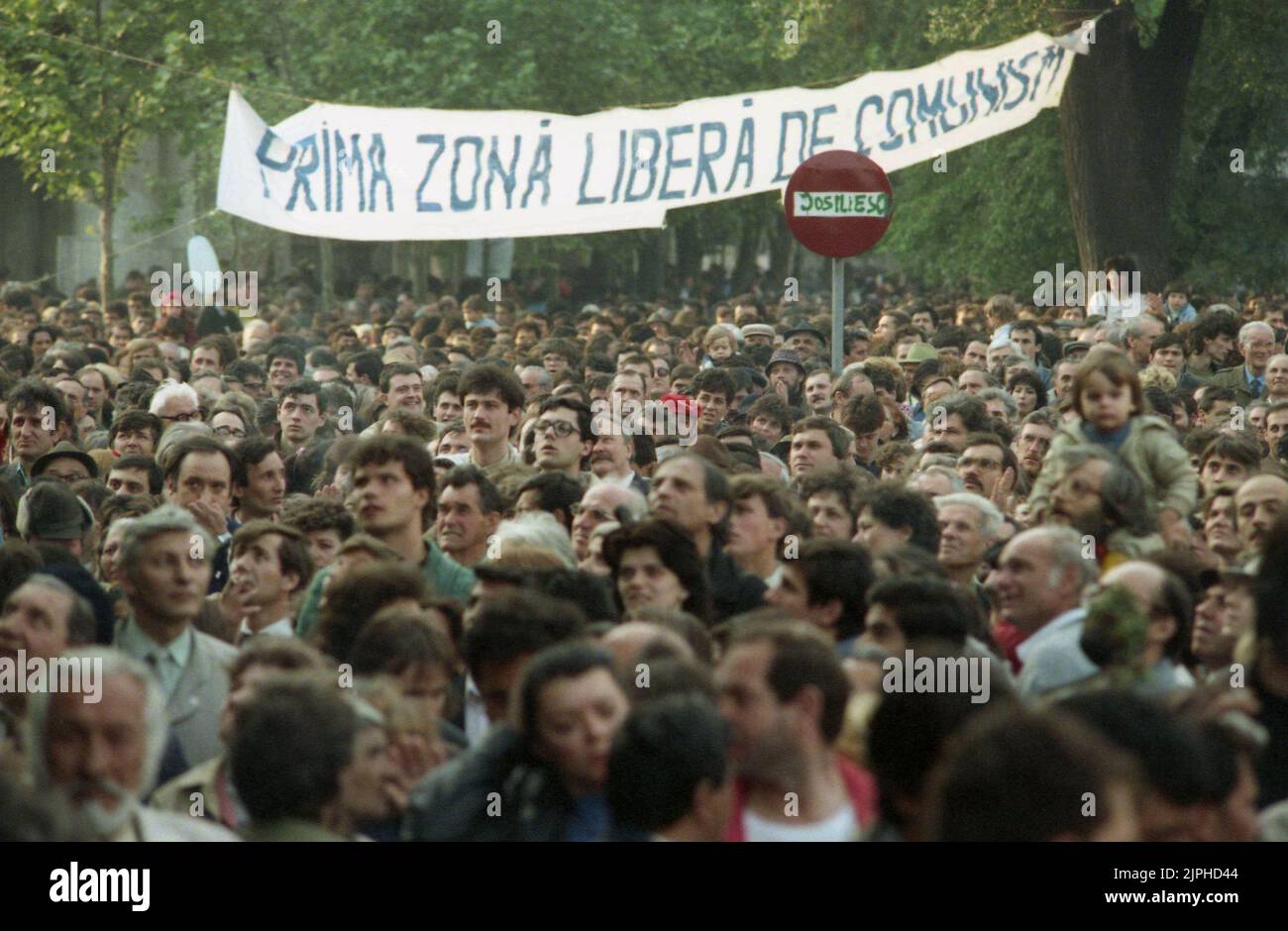 Bukarest, Rumänien, April 1990. Golaniada, ein großer Anti-Kommunismus-Protest auf dem Universitätsplatz nach der Revolution von 1989. Die Menschen versammelten sich täglich, um gegen die Ex-Kommunisten zu protestieren, die nach der Revolution die Macht ergriffen haben. Auf einem Straßenschild steht 'Jos Iliescu' (Down with Iliescu). Iliescu, ein ehemaliger kommunistischer Beamter, wurde nach der Revolution provisorischer Präsident und wurde schließlich bei den umkämpften Wahlen im Mai 1990 zum Präsidenten gewählt. Auf dem Banner steht: „Erste Zone frei vom Kommunismus“. Stockfoto