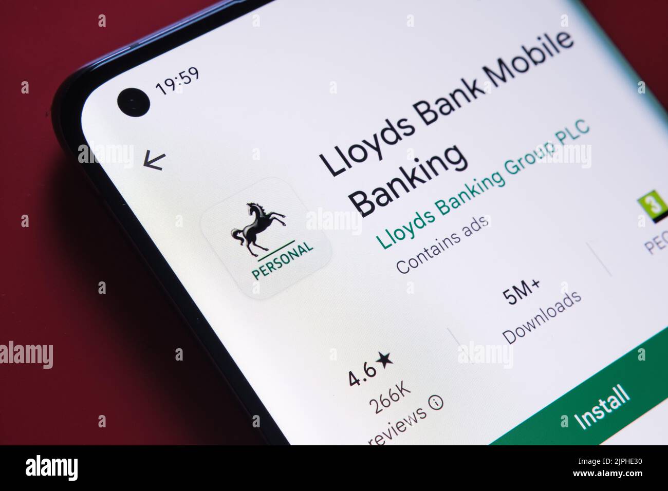 lloyds Banking-App im Google Play Store auf dem Smartphone-Bildschirm auf rotem Hintergrund platziert gesehen. Nahaufnahme mit selektivem Fokus. Stafford, United Stockfoto