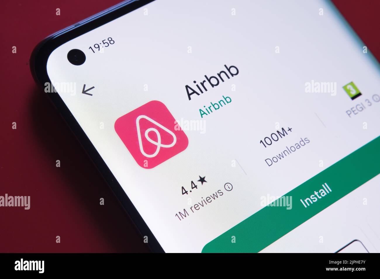 airbnb App im Google Play Store auf dem Smartphone-Bildschirm auf rotem Hintergrund gesehen. Nahaufnahme mit selektivem Fokus. Stafford, Vereinigtes Königreich, Stockfoto
