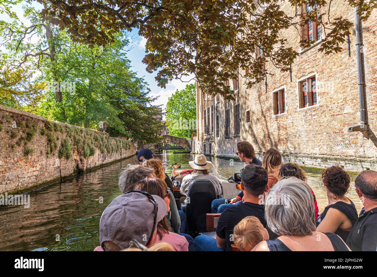Touristen genießen eine geführte Bootsfahrt um die Kanäle in Brügge, Belgien Stockfoto