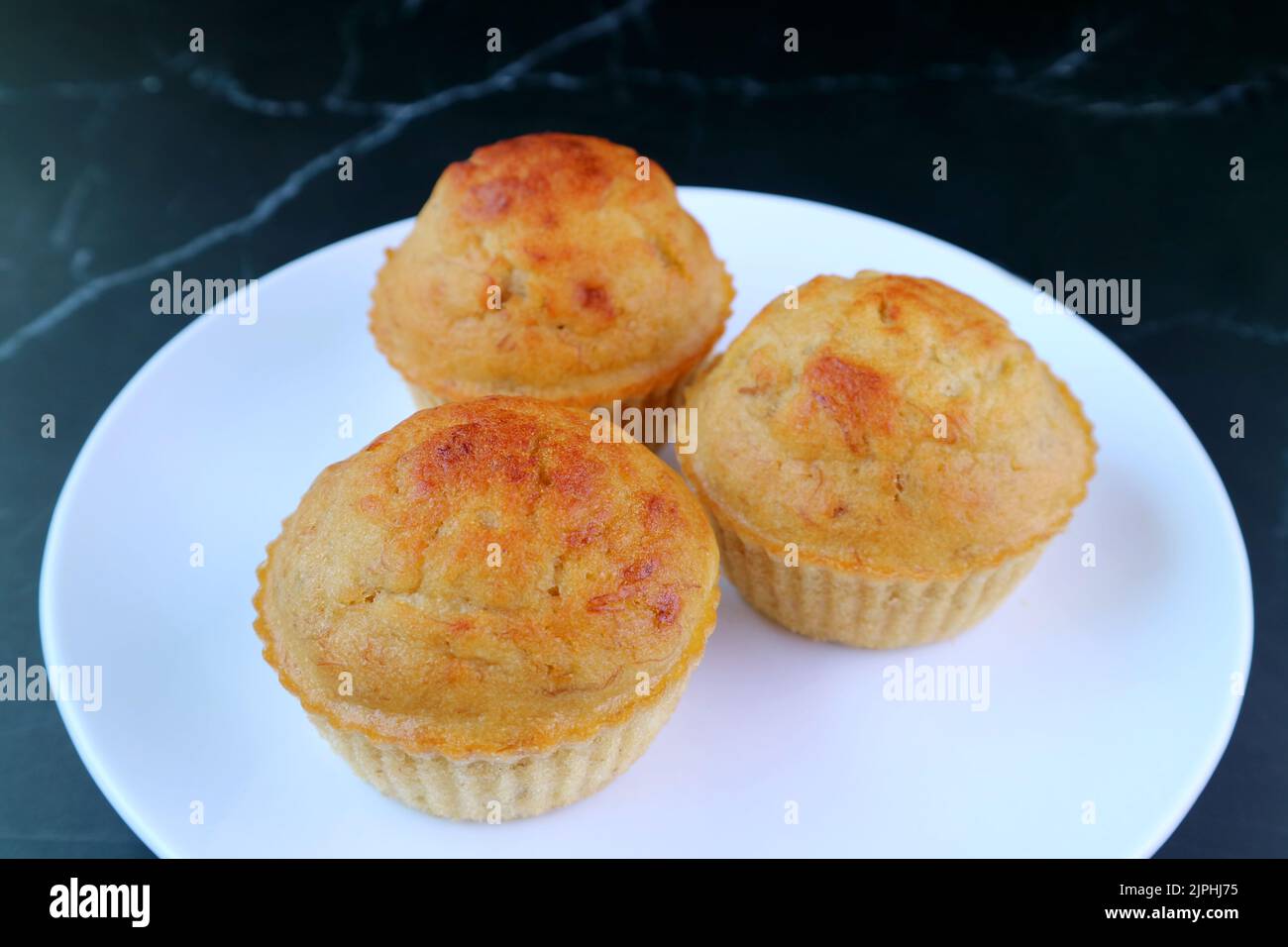 Ein Teller mit leckeren Bananenmuffins auf dem Tisch aus schwarzem Marmor Stockfoto