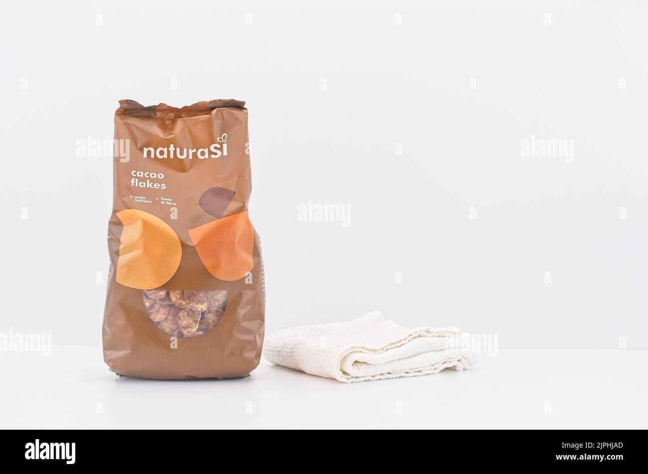 Kakao-Maisflocken aus biologischem Anbau in einer braunen Packung auf einem Tisch zusammen mit Geschirr Stockfoto