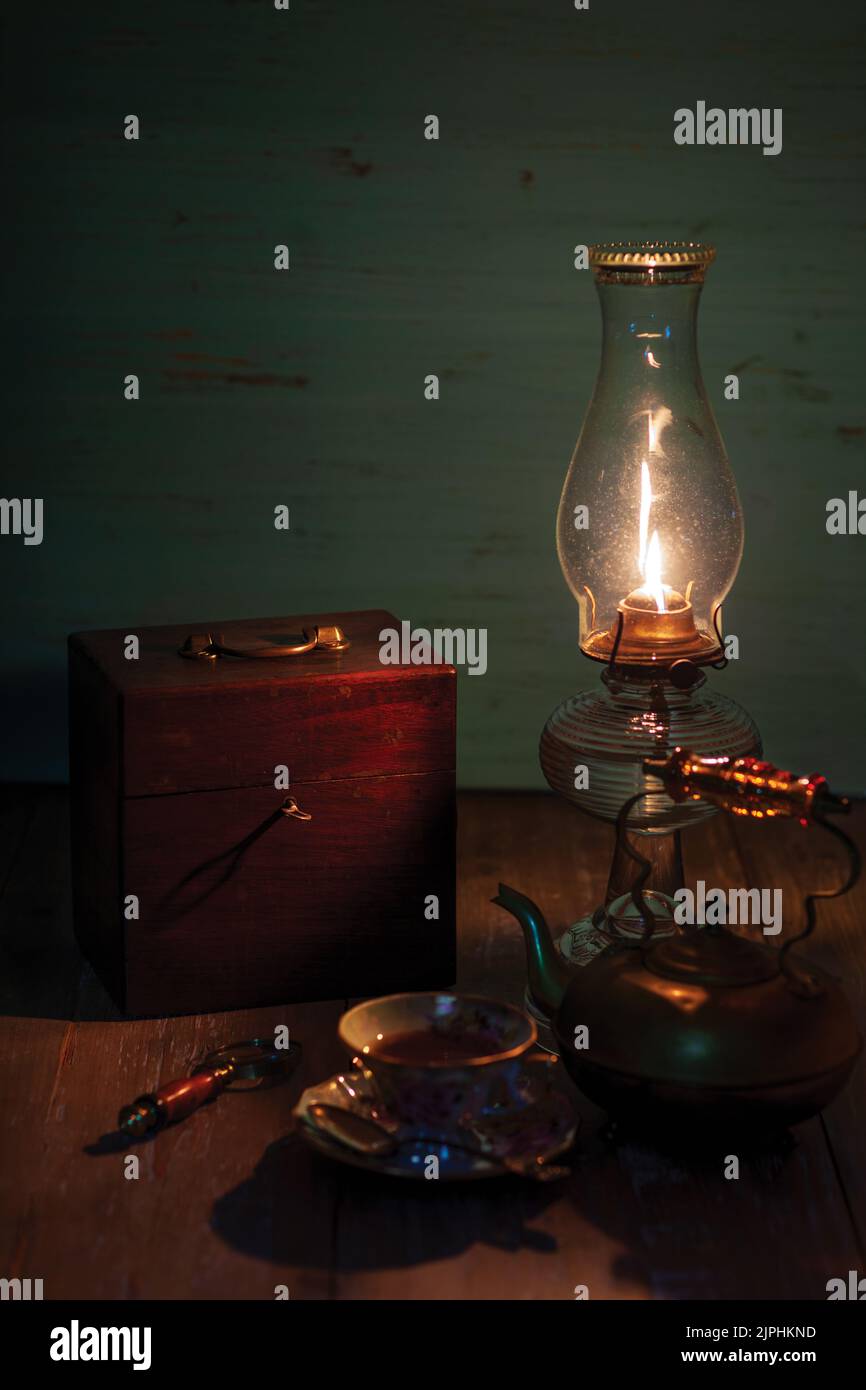 Stillleben mit Öllampe und alter Holzkiste und Teetaste und Wasserkocher auf Holztisch Stockfoto