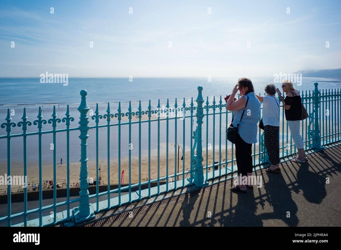 Drei ältere Frauen blicken von der erhöhten Fußgängerbrücke über den Strand von Scarborough Stockfoto