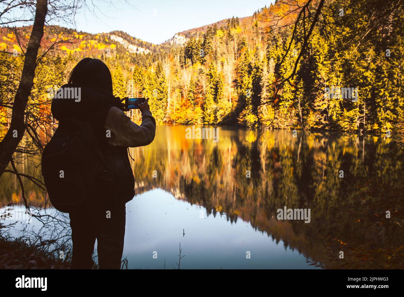 Nahaufnahme filmische Rückansicht kaukasische Frau Wanderer stehen am See Nehmen Sie Foto der malerischen Herbstnatur im Freien an sonnigen Tag im Freien. Berühmte Reise des Stockfoto