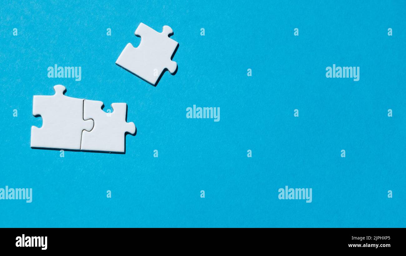 Weiße Puzzleteile auf dem blauen Hintergrund. Konzept des Brettspiels. Stockfoto