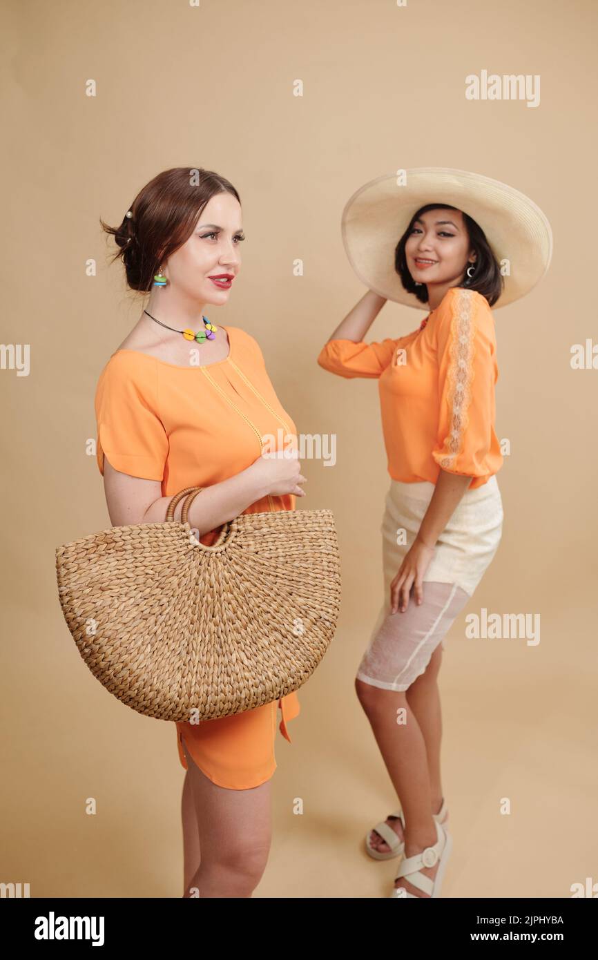 Junge Frauen in leuchtend orangefarbenen Outfits posieren im Fotostudio für den Modekatalog Stockfoto