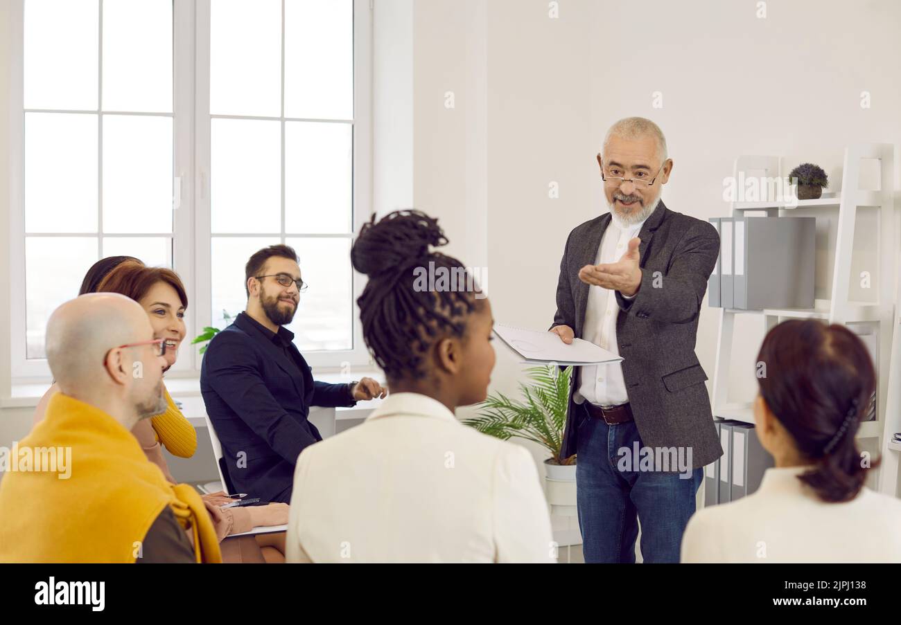 Der leitende männliche Manager des Unternehmens hält ein geplantes Geschäftsmeeting mit seinen Mitarbeitern im Büro ab. Stockfoto