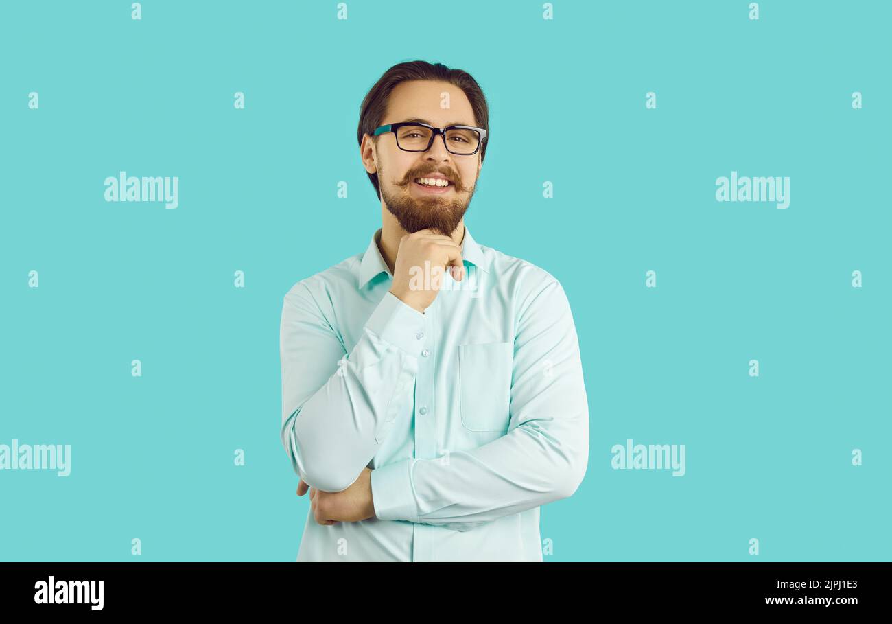 Porträt auf hellblauem Hintergrund eines gutaussehenden lächelnden Geschäftsmannes mit stilvollem Schnurrbart und Bart. Stockfoto