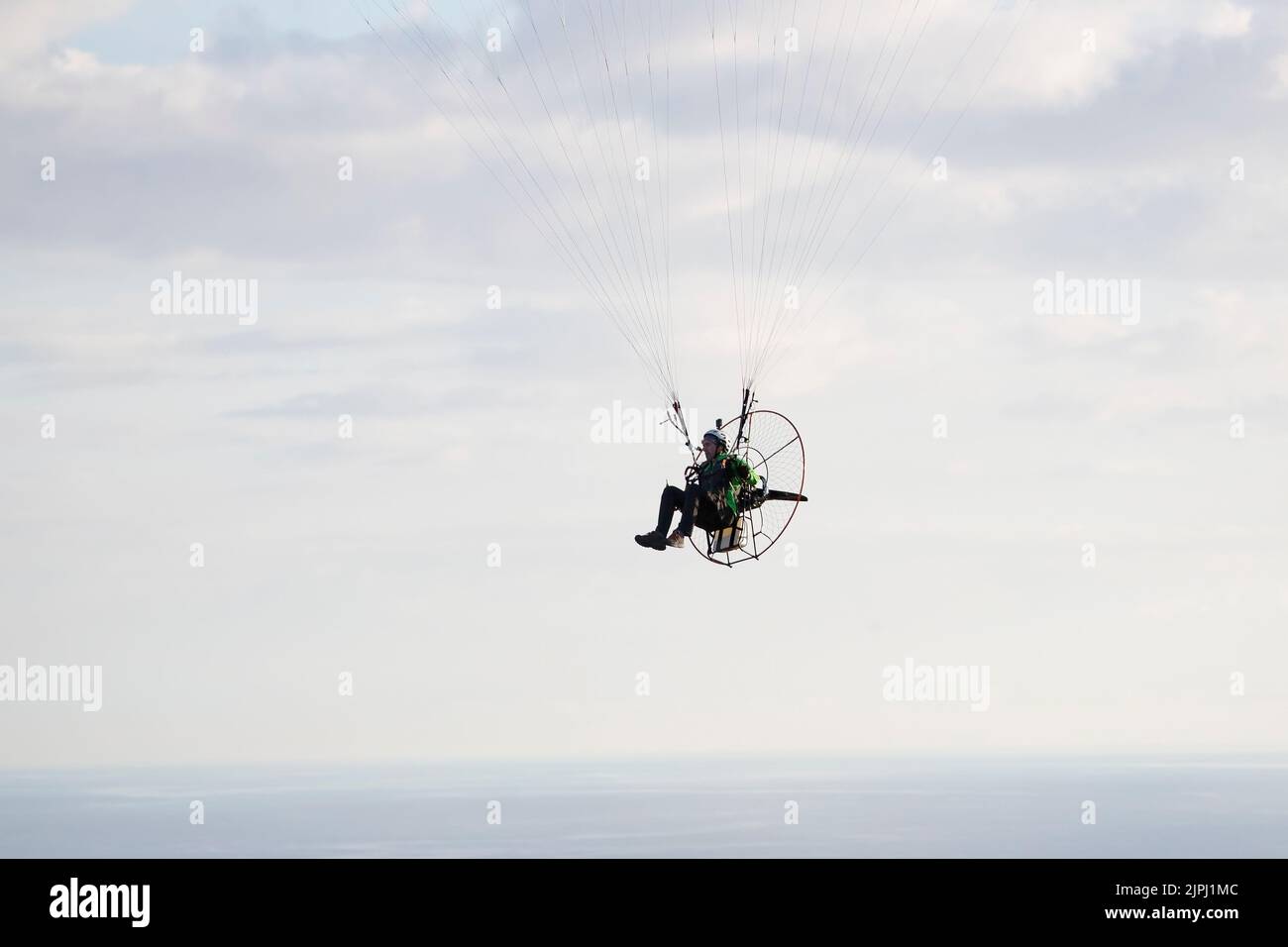 Ein Paramotor-Pilot, der nach einem Alleinflug über der Great Orme in Llandudno, Nordwales, an einem klaren und frühen Sommermorgen vor der Landung absteigt Stockfoto