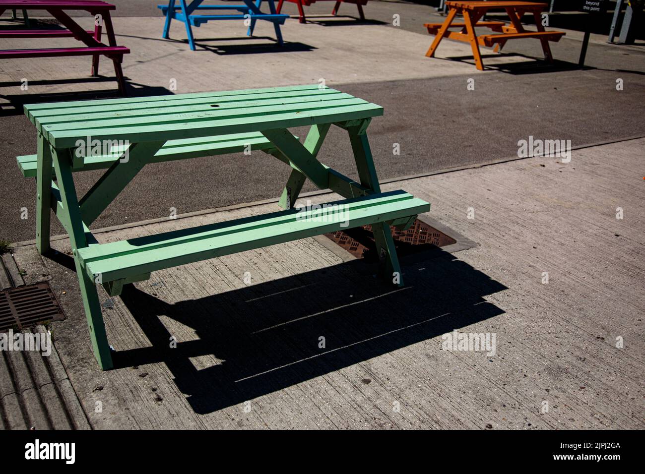 Bunte Picknickbänke auf einem Marktplatz an einem sonnigen Tag Stockfoto