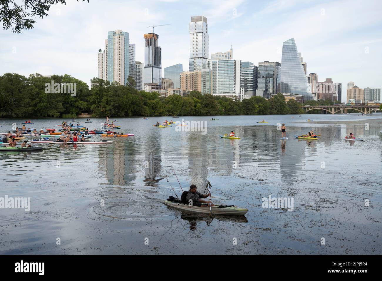 Paddler aller Art, einschließlich Stand-up-Paddleboards und aufblasbare Kajaks, genießen an einem heißen Augustabend das kühle Wasser des Lady Bird Lake in der Nähe des Zusammenflusses von Barton Creek und dem Colorado River in der Innenstadt von Austin. ©Bob Daemmrich Stockfoto