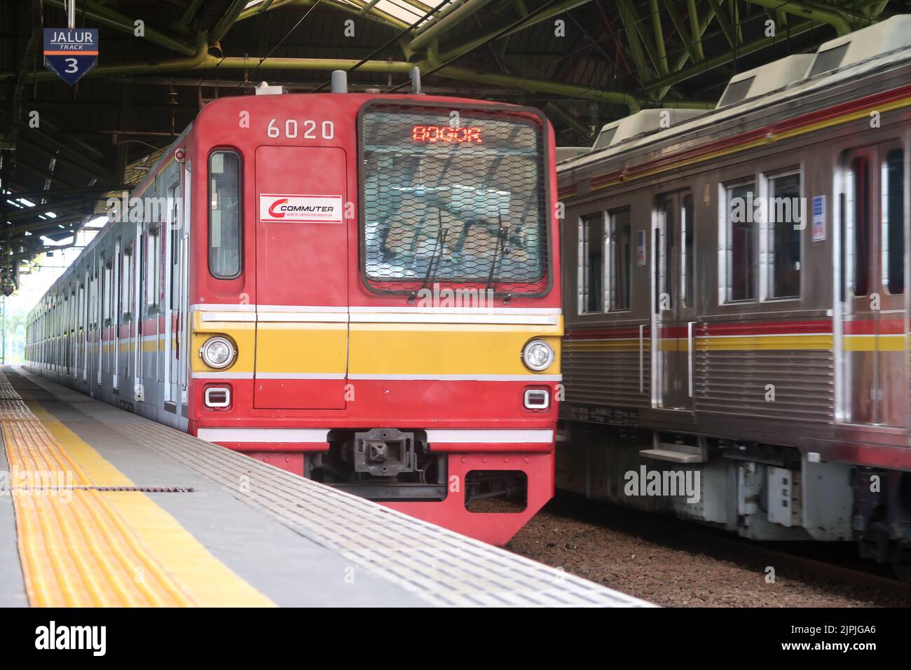 Ein roter indonesischer Pendlerzug, der durch den Bahnhof Gambir, Jakarta, fährt Stockfoto