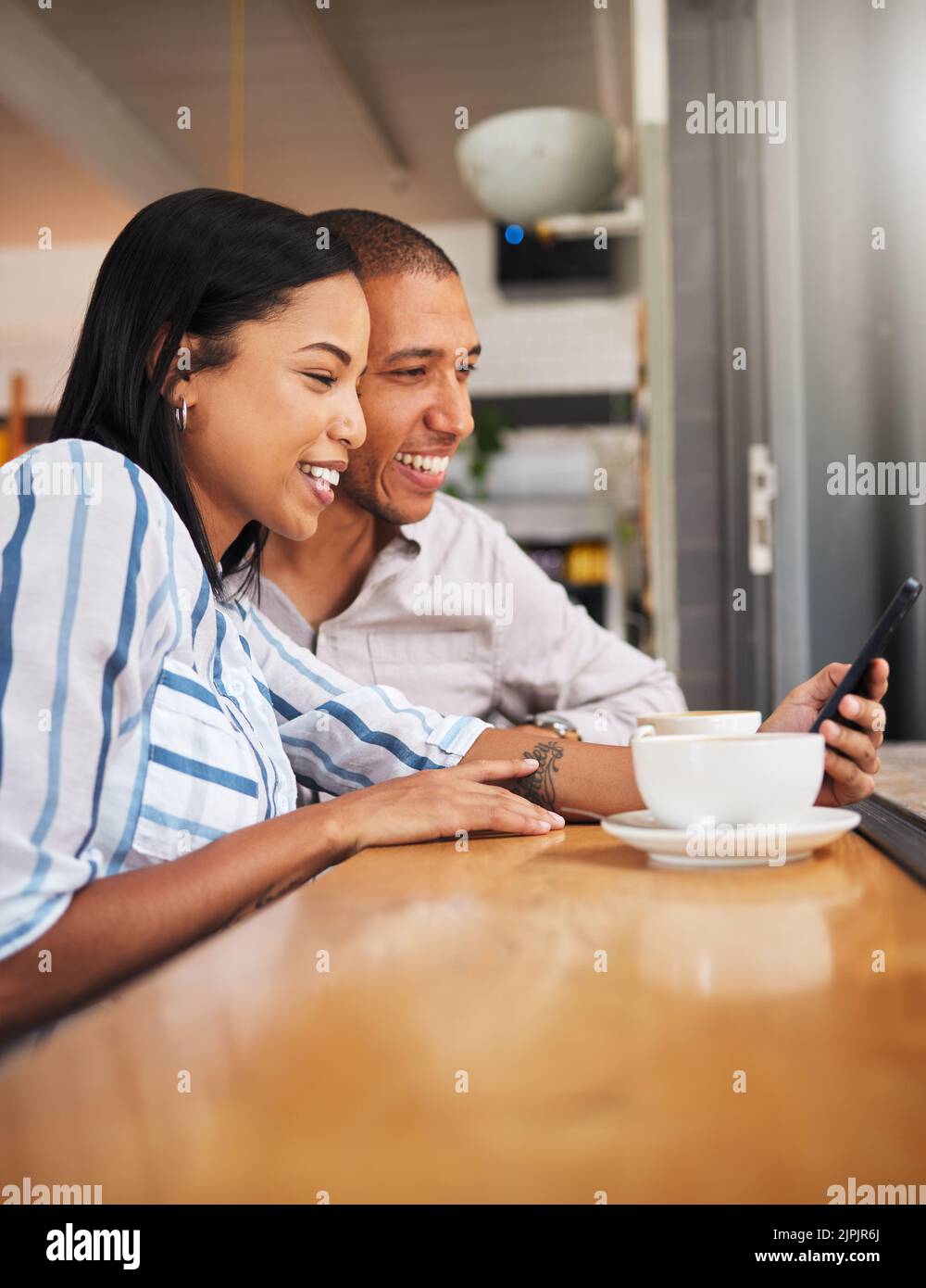 Glückliches Paar, das am Telefon die sozialen Medien liest und sich bei einem Pflegebedürften auf eine Kaffeepause einlässt. Lächelnder Freund und Freundin, die online surfen, suchen nach Stockfoto