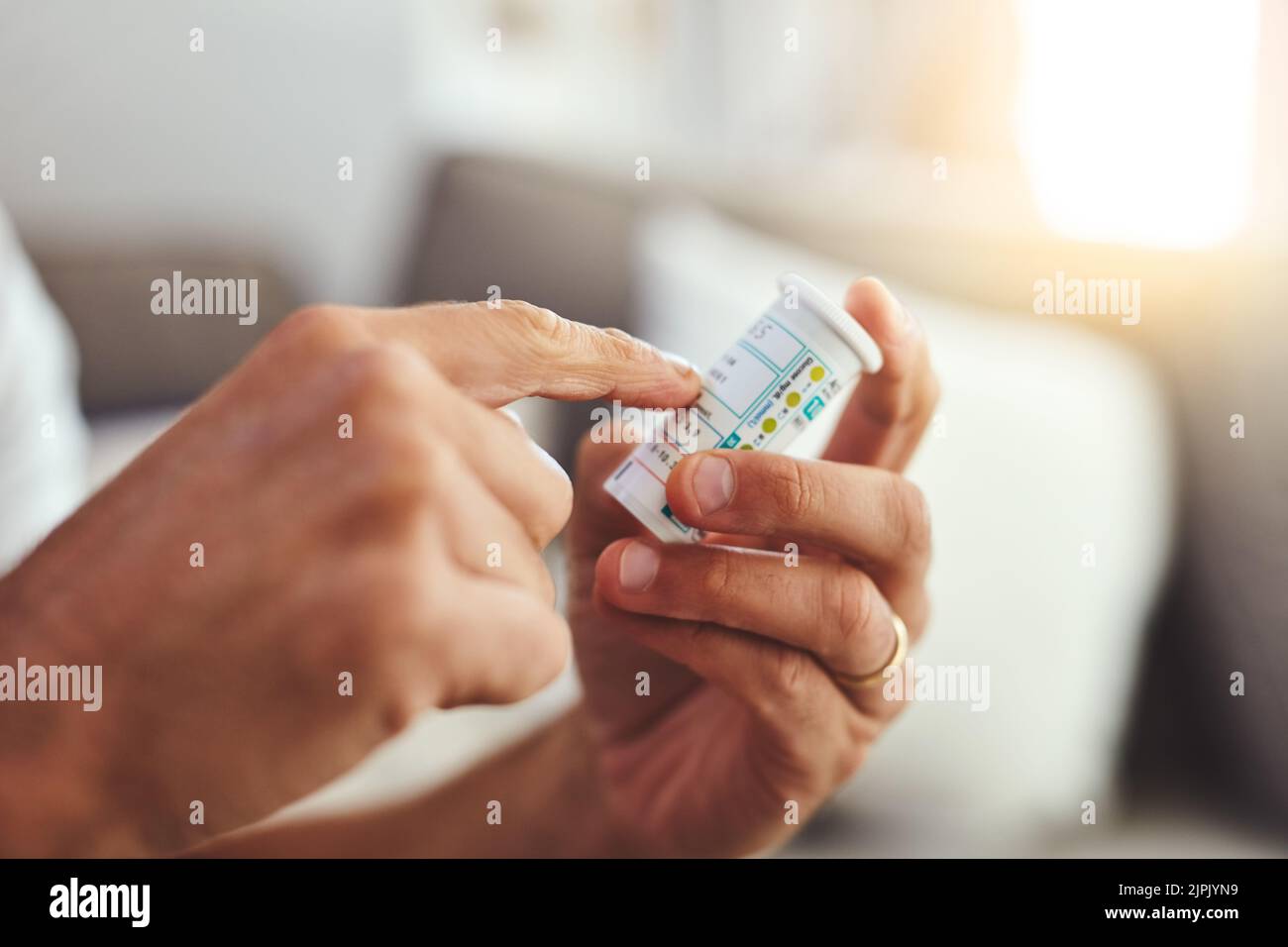 Kontrolle der Dosierung. Ein nicht erkennbarer junger Mann, der seine Medikamente zu Hause einnehmen wird. Stockfoto
