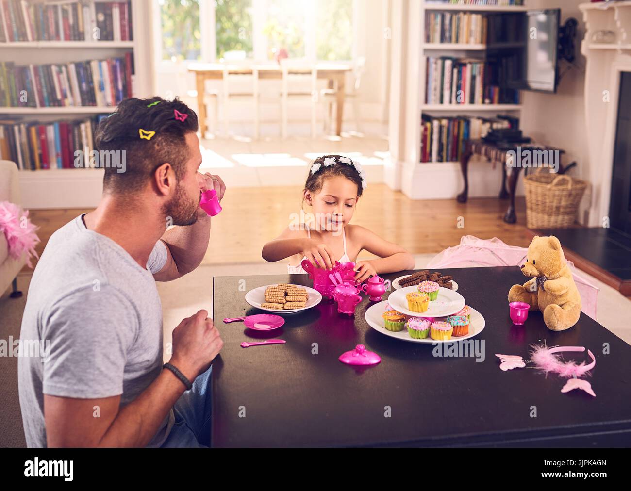 Es ist eine königliche Teeparty. Ein Vater und seine kleine Tochter, die zu Hause eine Teeparty machen. Stockfoto