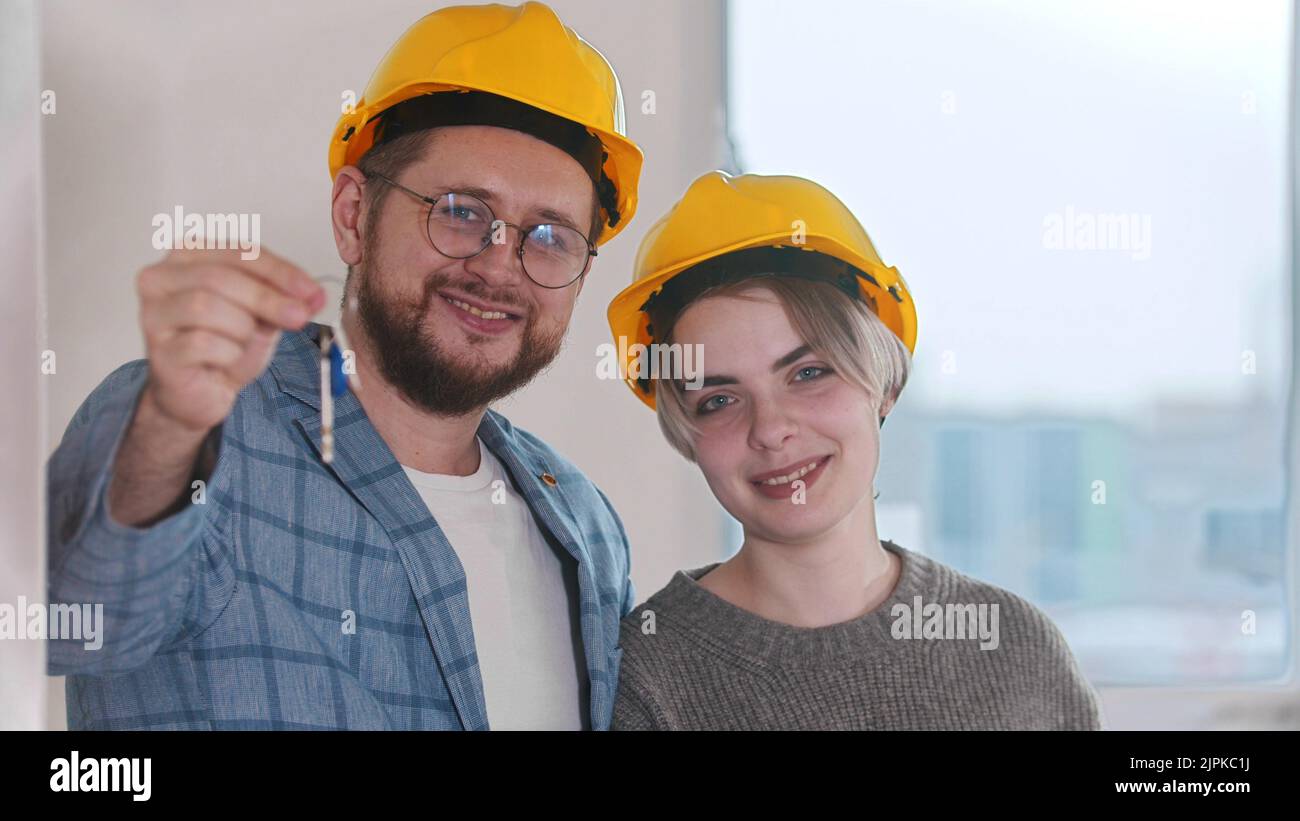 Glückliche, schwanger Frau mit ihrem Mann, der Schlüssel aus der neuen Wohnung hat. Mittlerer Schuss Stockfoto
