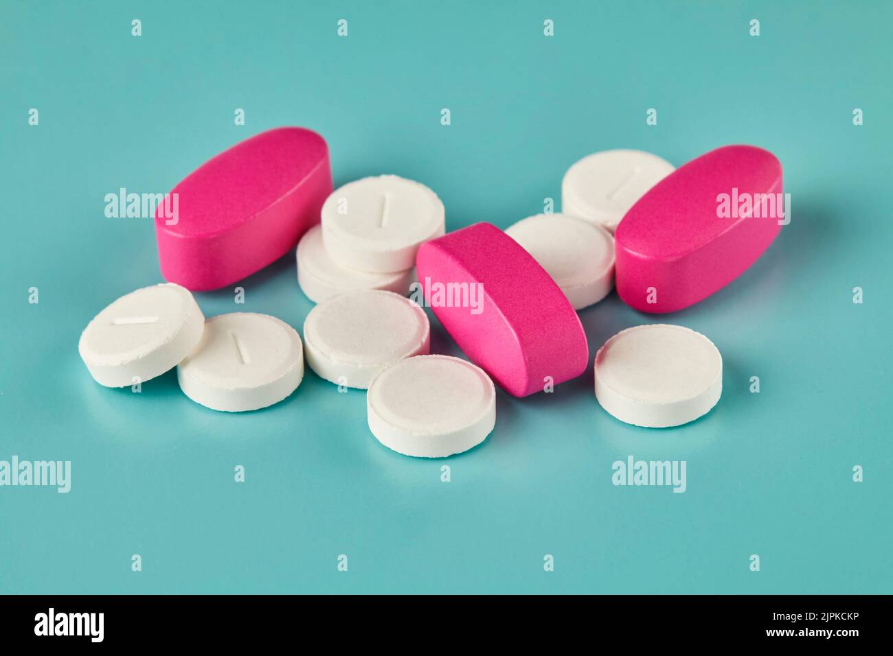 Medizin weiße Tabletten und rosa Kaplets auf cyanfarbenem Hintergrund Stockfoto