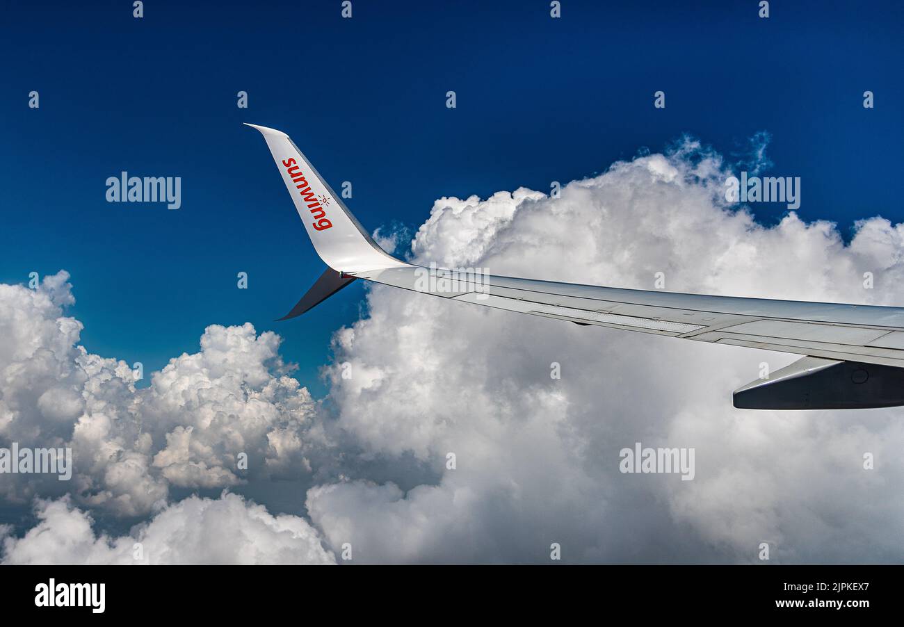 Rückkehr aus dem Urlaub in Holguin Kuba. Vor dem Hintergrund schwerer Wolken über dem Atlantik fliegt ein Sunwing-Flugzeug über die Küste Kubas. Stockfoto