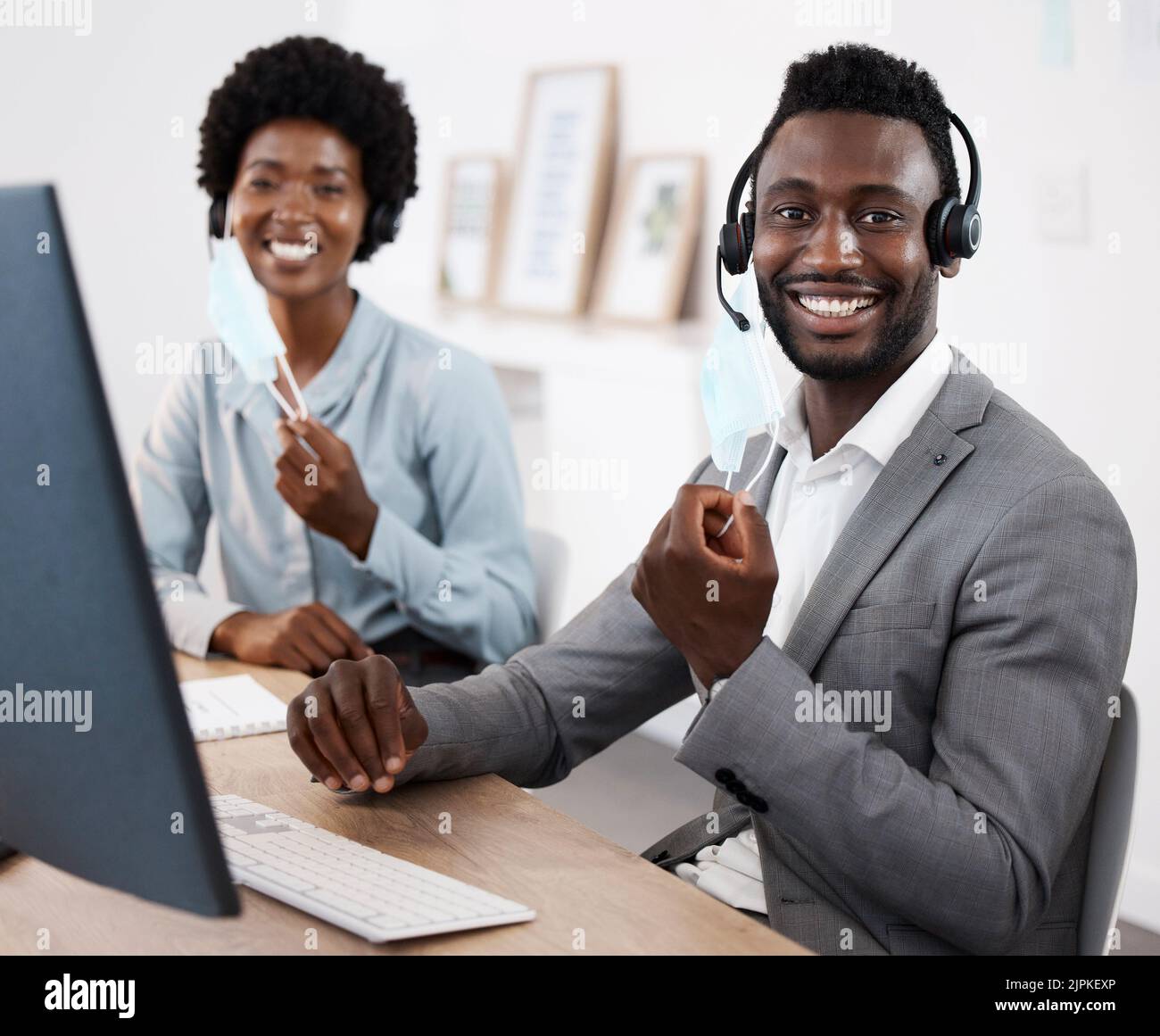 Kundendienstmitarbeiter, die am Computer arbeiten, Menschen online helfen und Unterstützung leisten, während sie zusammen bei der Arbeit sitzen. Porträt eines lächelnden afrikanischen Anrufs Stockfoto