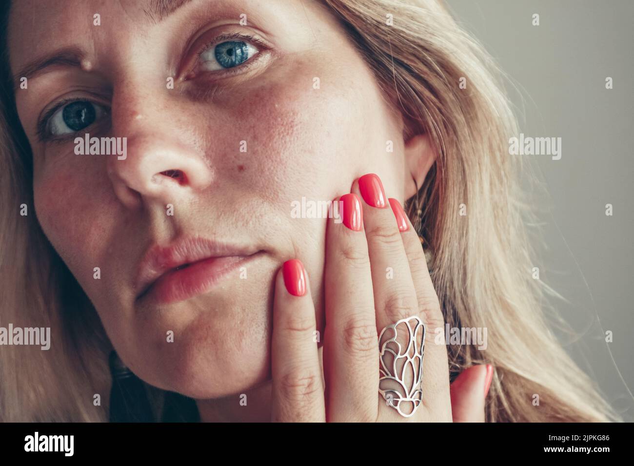 Schöne Frau mittleren Alters zeigt rote Schellack Maniküre auf Nägeln. Stockfoto
