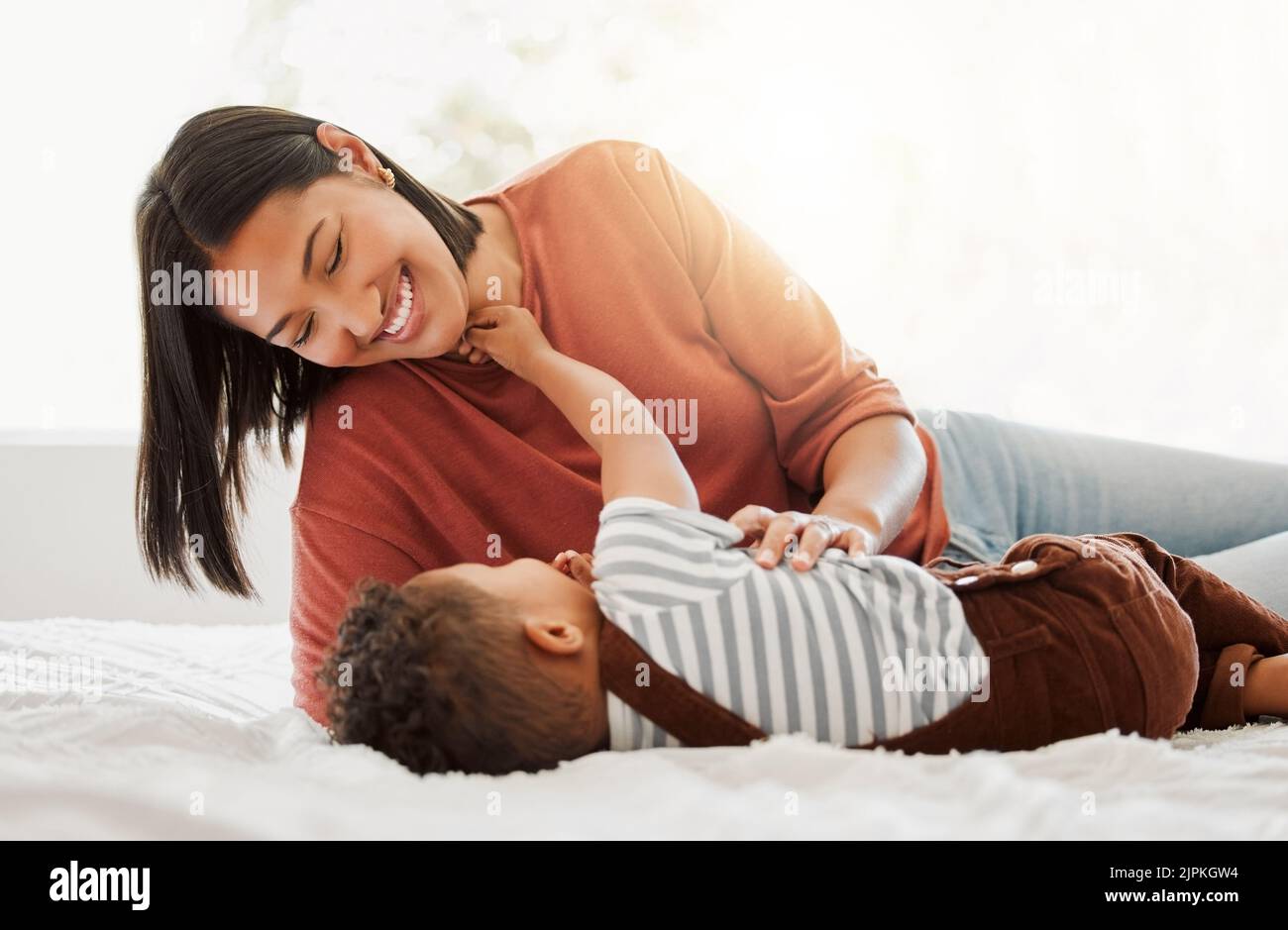 Glücklich, Liebe und Familie Zeit mit einer Mutter und Sohn, die verspielt und Bindungen auf einem Bett zu Hause. Eltern spielen mit ihrem Kind, lächeln und genießen Stockfoto