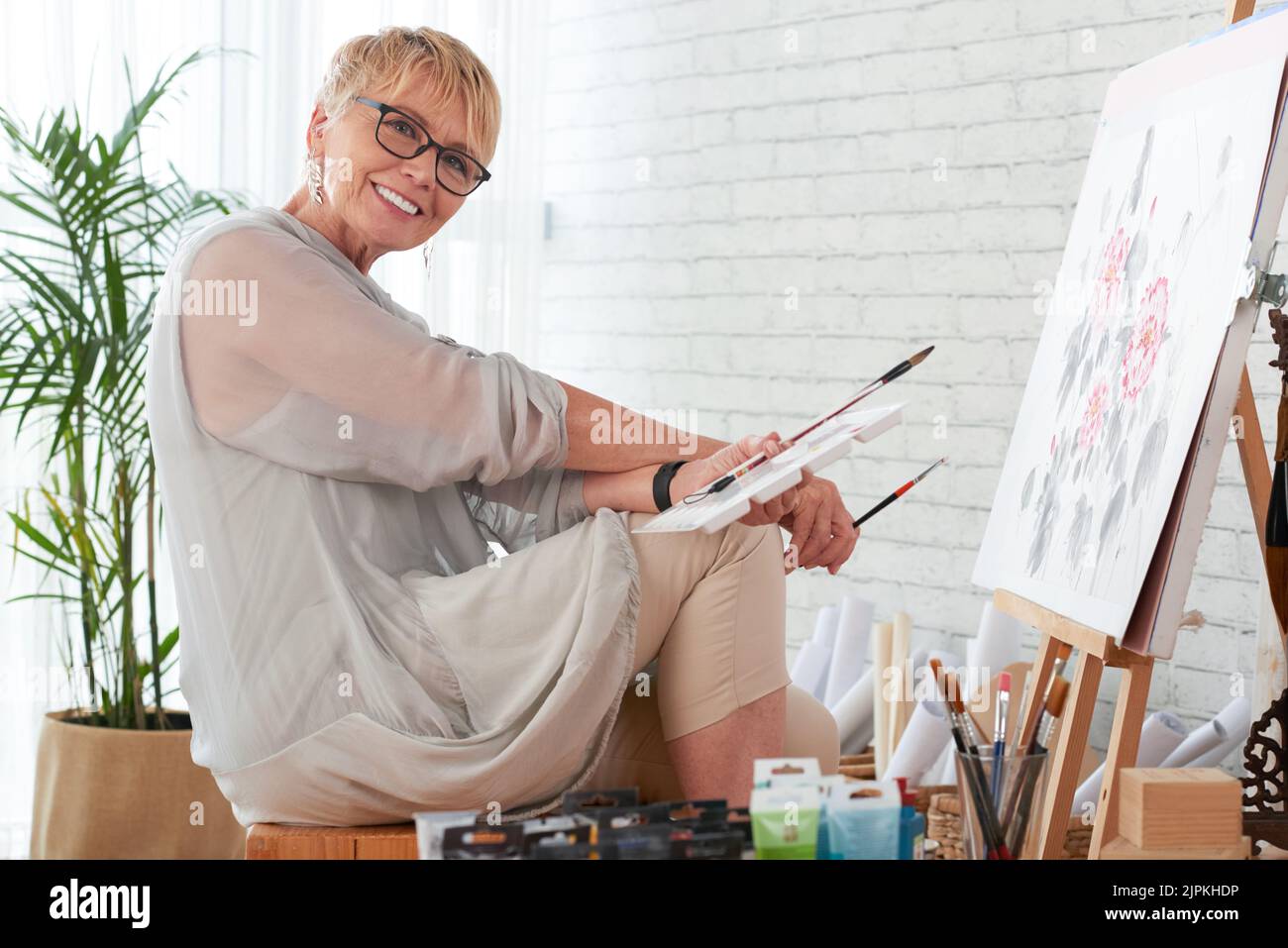Porträt einer glücklichen, kreativen älteren Frau in ihrem Heimstudio Stockfoto