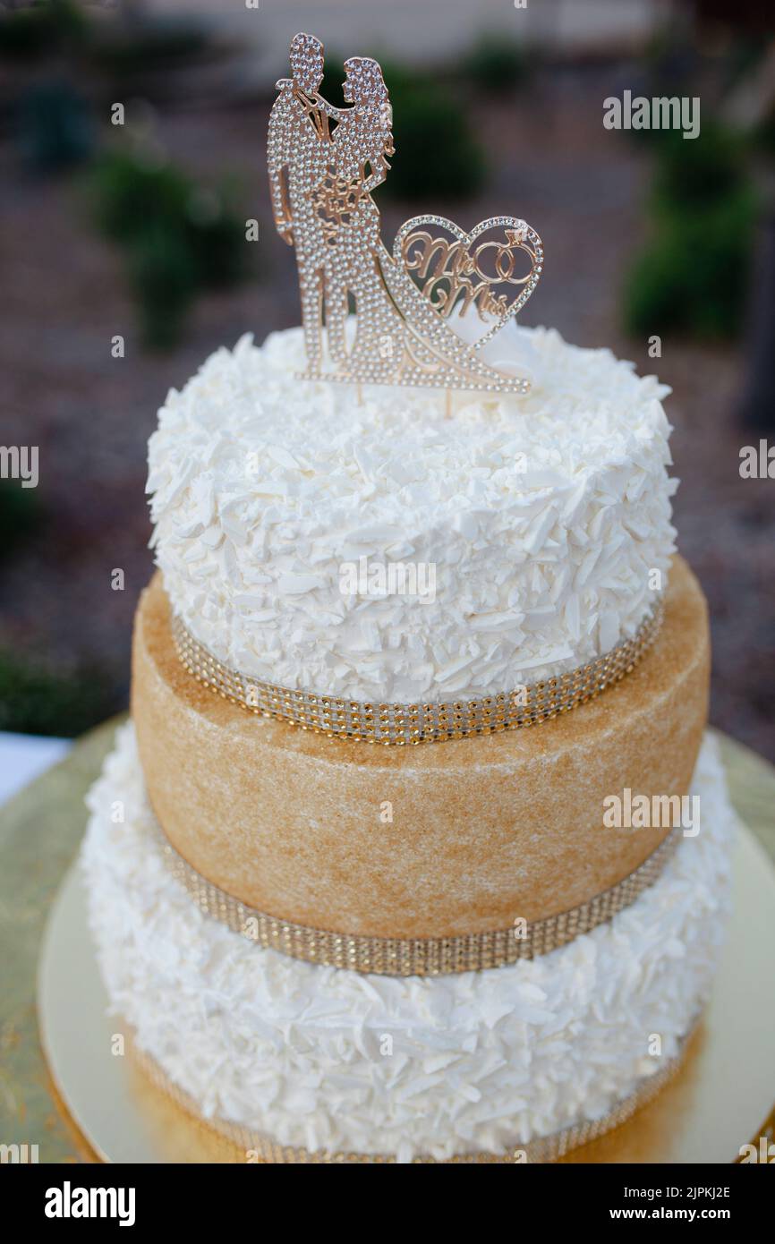 Weiße und goldene Hochzeitstorte mit Figuren und Rippensteinen. Stockfoto