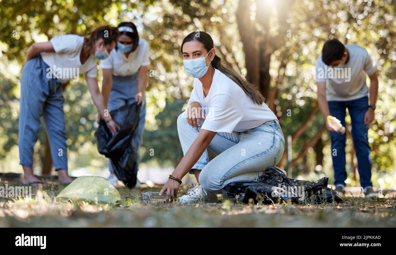 Covid, Freiwillige und Wohltätigkeitsorganisation mit einer jungen Frau, die gemeinschaftsdienstlich arbeitet und die Umwelt mit den Menschen im Hintergrund reinigt. Porträt eines Stockfoto