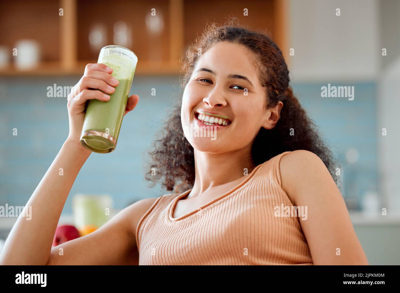 Grüner Smoothie, trinken und gesunden Saft für die Gewichtsabnahme, Entgiftung oder Frühstück Diät im Wohnzimmer zu Hause. Porträt einer lächelnden, glücklichen Frau, die Obst trinkt Stockfoto